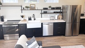 A modern kitchen with dark cabinets, stainless steel appliances, and a wooden countertop.