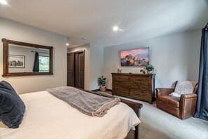 Une chambre à coucher avec un lit, une commode, une chaise, un miroir et un tableau accroché au mur.