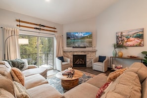 A living room with a fireplace, a television, and a balcony with curtains.