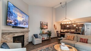 A living room with a fireplace, a television, a sofa, a coffee table, and a dining area.