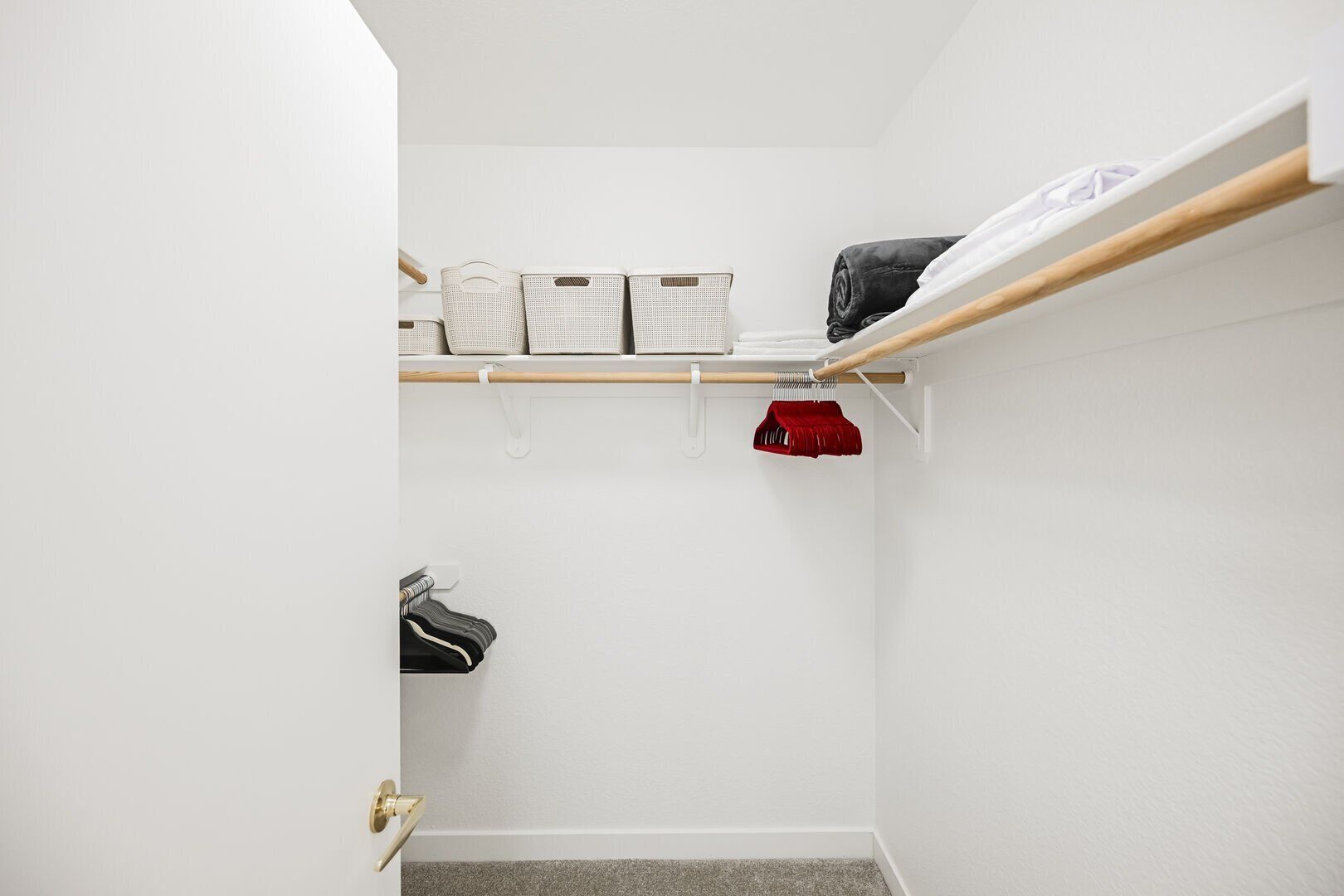 A walk-in closet with shelves, a hanging rod, and a shoe rack.