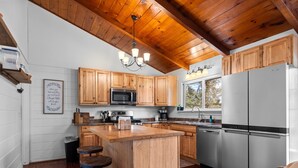 Una cocina con armarios de madera, un refrigerador de acero inoxidable, un microondas e isla de madera con taburetes.