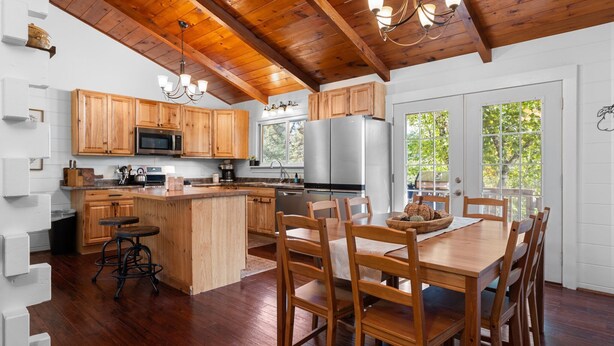 Una cocina moderna con armarios de madera, una isla central y un comedor con sillas de madera.