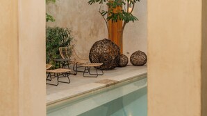 A pool area with a seating arrangement, a large tree, and decorative spherical objects. - Departamentos Central (Mérida)