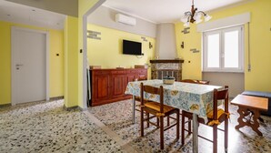 Un coin repas avec une table dressée pour quatre personnes, un téléviseur fixé au mur et une cheminée.