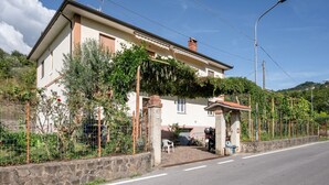 Une maison à deux étages avec un mur en pierre, un porche couvert et une moto garée.