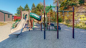 Un parque infantil con tobogán, estructuras para escalar y una zona cubierta.