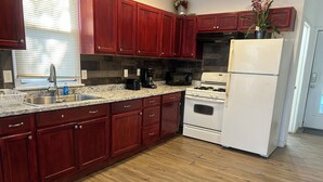 Una cocina con armarios de madera, encimera de granito, refrigerador blanco y estufa.
