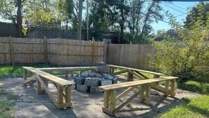 Une terrasse en bois avec un foyer au centre, entourée de bancs.