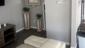 Un salon comprenant un canapé, une petite table, deux consoles décoratives ornées de plantes, un miroir et un escalier menant à un niveau supérieur.
