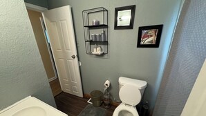 A bathroom with a white sink, toilet, and a small shelf with toiletries.