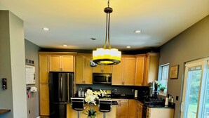 A modern kitchen with wooden cabinets, stainless steel appliances, and a wooden dining table with benches.