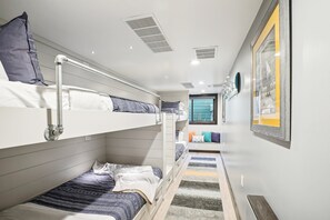 Ein Schlafzimmer mit Etagenbetten, einem Fenster, einem gerahmten Bild an der Wand und einem gemusterten Teppich.