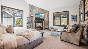 A spacious living room with a large bed, a fireplace, a comfortable sofa, and a television.