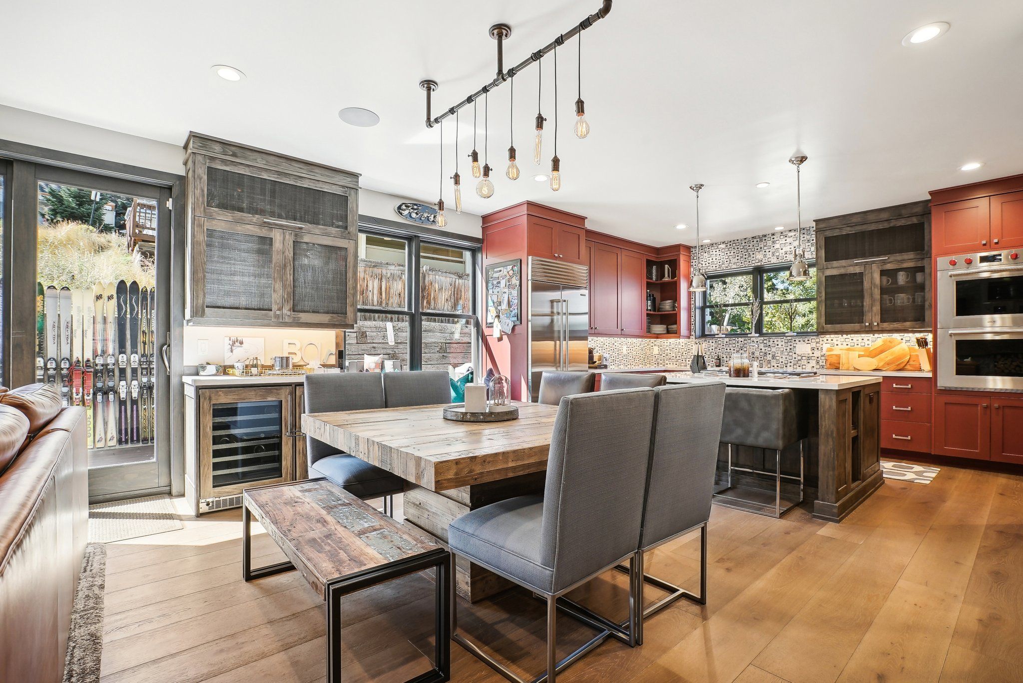 Een moderne keuken met een eethoek, met een houten tafel, stoelen en een hanglamp.