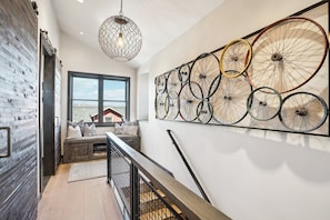 A modern interior with a staircase, a wall-mounted bicycle wheel art piece, and a hanging light fixture. - Last Chair at Park City-Near Town Lift! Hot Tub! (Park City)