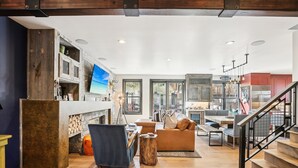 A spacious living area with a fireplace, a sofa, a dining table, and a staircase.
