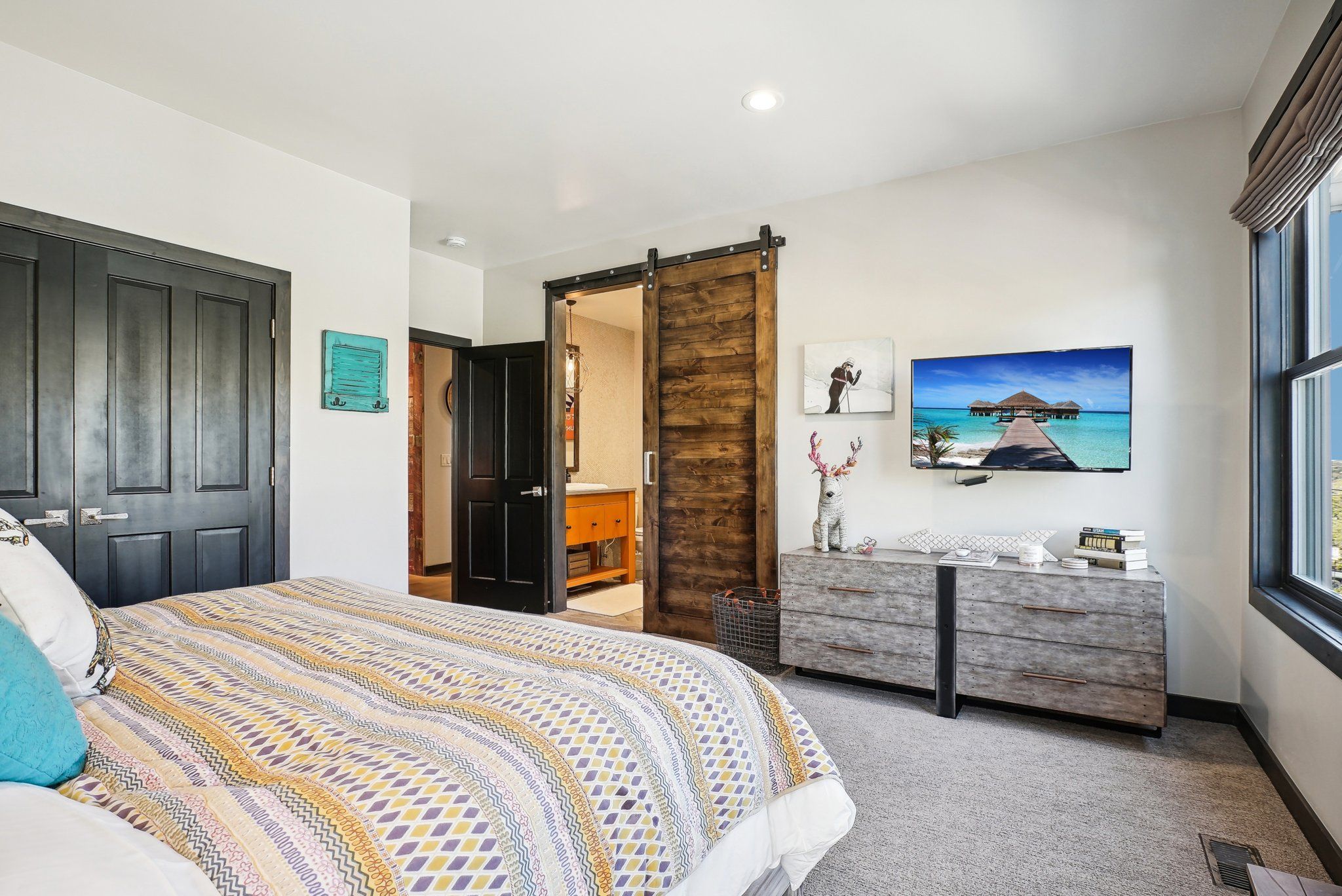 Une chambre à coucher avec un lit, une commode, un tableau et une fenêtre.