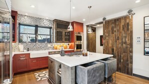 A modern kitchen with a central island, wooden cabinets, and pendant lighting.