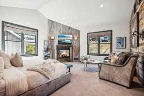 A spacious bedroom with a large bed, a fireplace, a television, and a view of the outdoors.