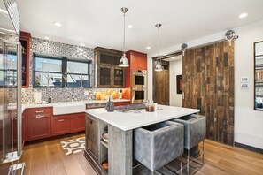 A modern kitchen with a central island, wooden cabinets, and a large window. - Last Chair at Park City-Near Town Lift! Hot Tub! (Park City)