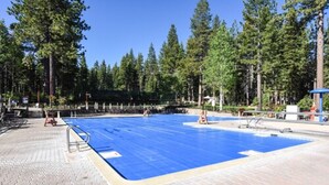Una piscina amb superfície blava, envoltada d'arbres i un passeig de rajol.