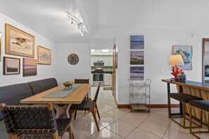 Un comedor moderno con una mesa de madera, sillas con cojines y obras de arte en las paredes.
