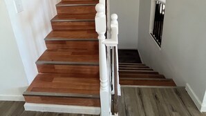 Una escalera con escalones de madera y barandillas blancas.