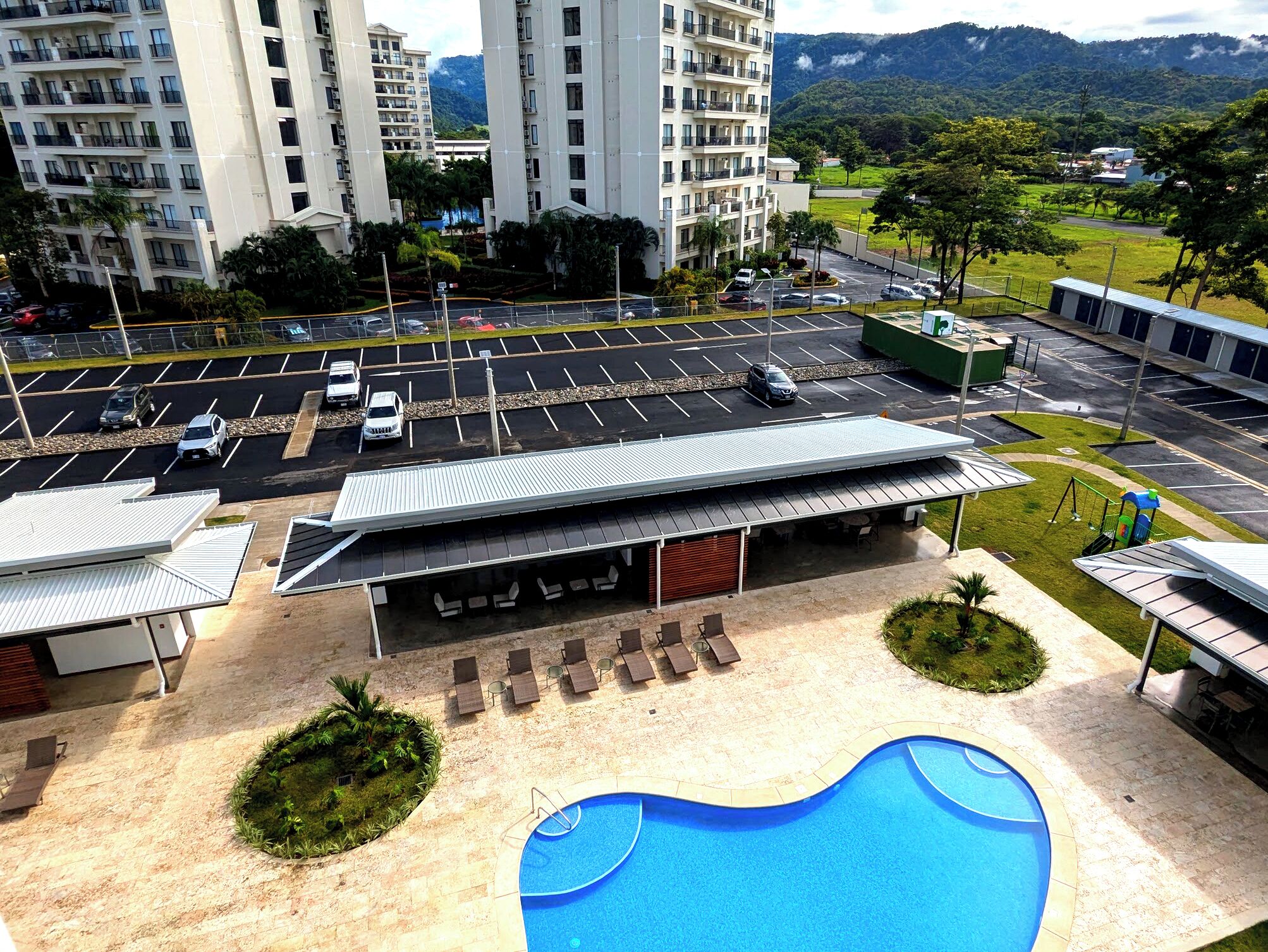Hotel med swimmingpool, parkeringsplads og udsigt til bjerge.