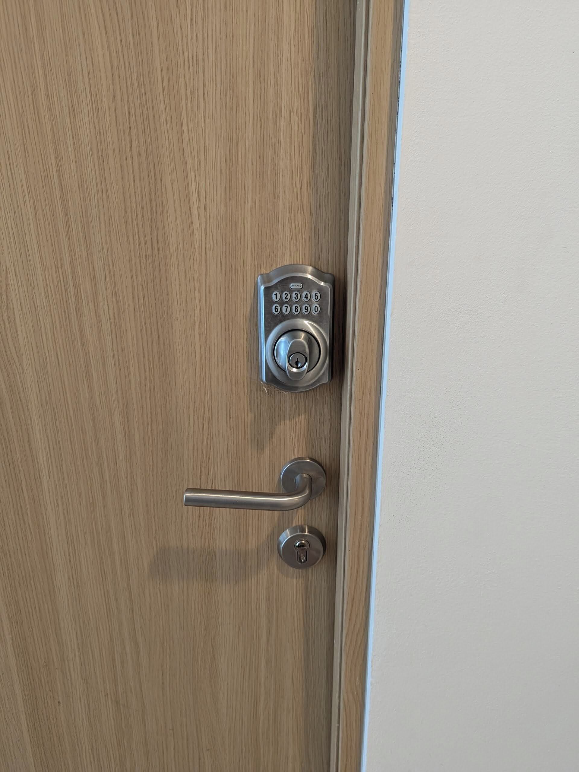 Eine Holztür mit Zahlenschloss und Drücker.