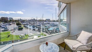 A balcony with a view of a marina, a dining area with outdoor seating, and a clear sky. - Coastal Charm – Breathtaking Views with Work Desk by Victoria Prime! (Victoria)