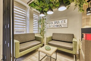 A modern lounge area with two sofas, a small table, and a sign indicating it's a 'HUB SUITE in Istanbul.' - Hub Suite Istanbul (Istanbul)