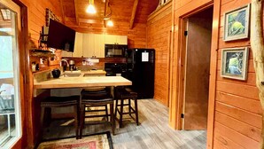 L’intérieur d’une cabane en bois comprend une cuisine, un coin repas et un escalier.