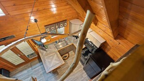 L’intérieur d’une cabane en bois comprend un espace cuisine équipé d’un poêle, d’un évier et de placards.