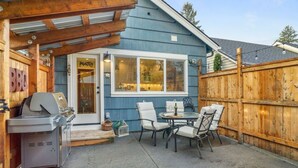 Un patio trasero con una parrilla, mobiliario exterior y una valla de madera.