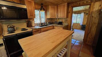 Une cuisine avec des meubles en bois, une cuisinière, un four à micro-ondes et un grand îlot central en bois.