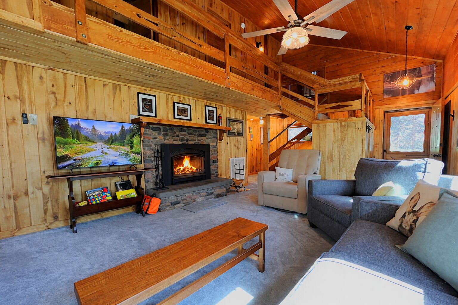 Un intérieur de chalet chaleureux avec une cheminée, un téléviseur et un coin salon confortable.
