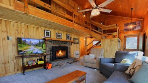Un interior de cabaña acogedor, con chimenea, televisor y un espacio de estar cómodo.