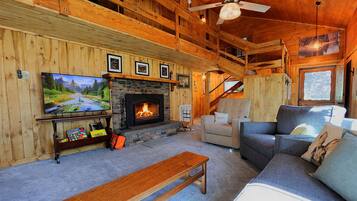 Un intérieur de chalet chaleureux avec une cheminée, un téléviseur et un coin salon confortable.
