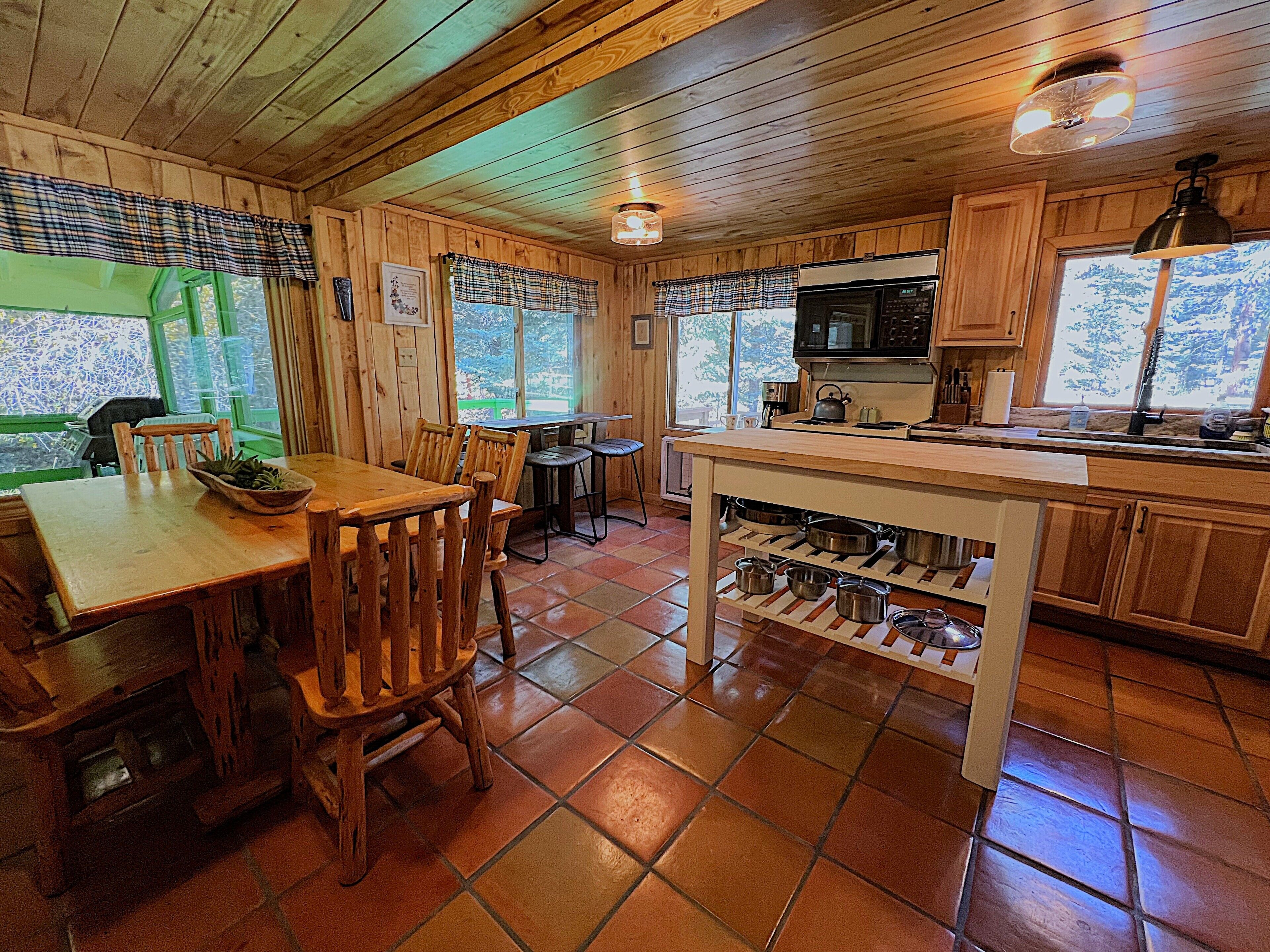 L’intérieur d’un chalet en bois comprend un coin repas, une cuisine et de grandes fenêtres.