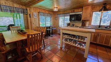 L’intérieur d’un chalet en bois comprend un coin repas, une cuisine et de grandes fenêtres.