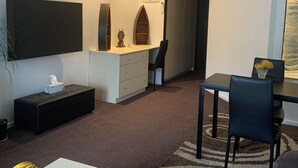 A modern living room with a flat-screen TV, a small dining area, and a cozy seating space.
