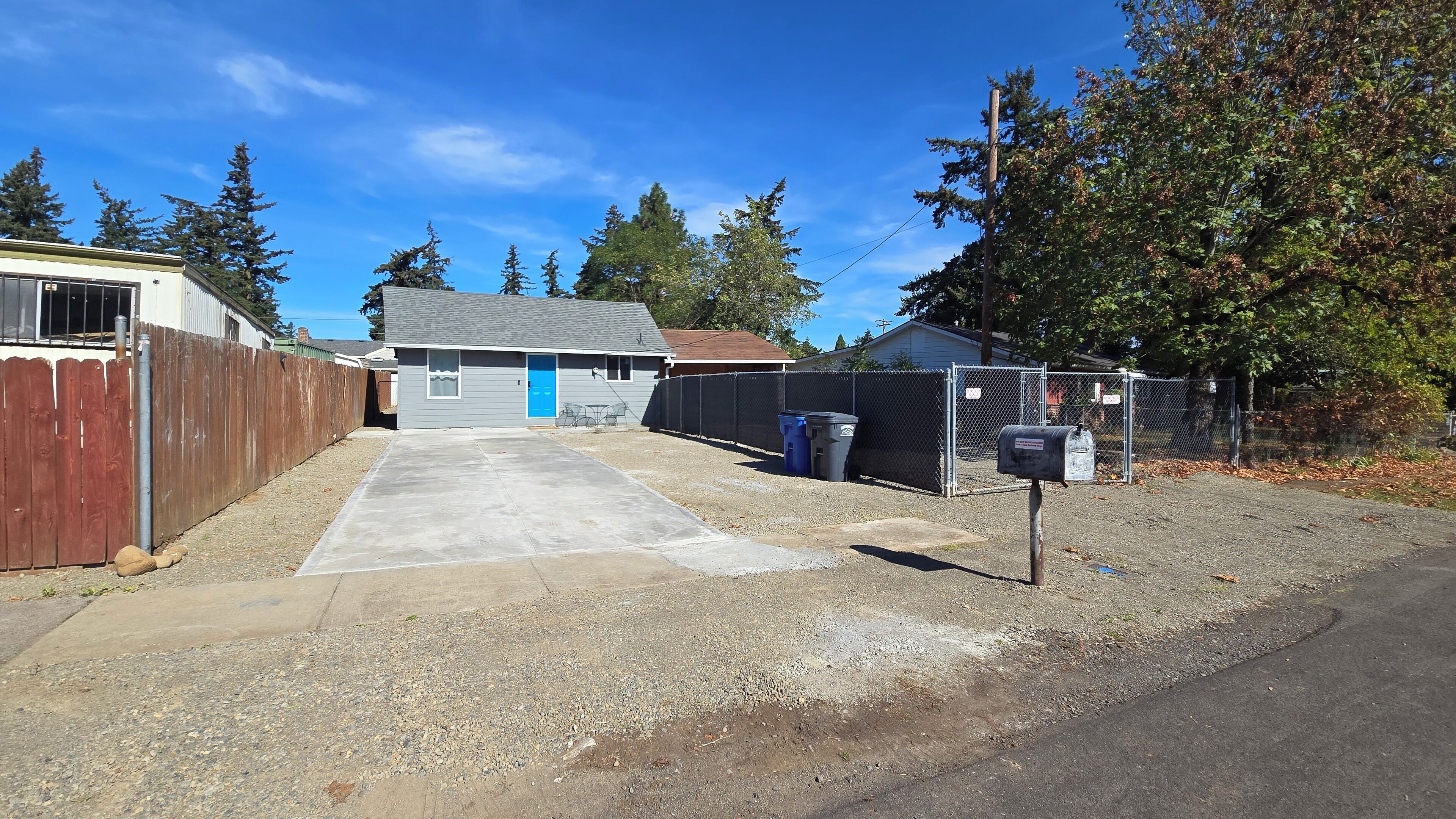 A residential garage with a concrete driveway, a blue door, and a metal fence.