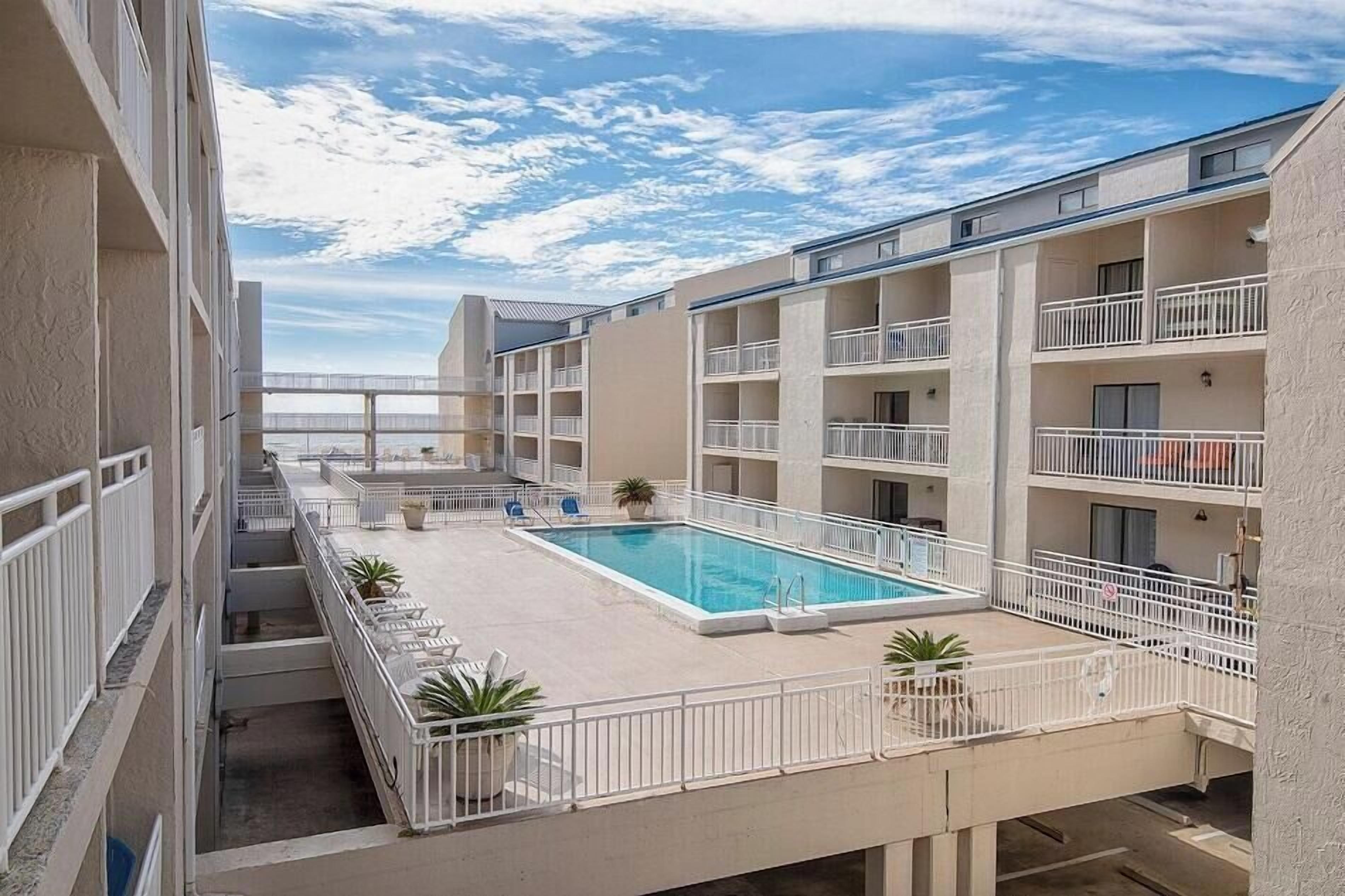 A hotel with a swimming pool, multiple balconies, and a view of the sea.