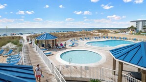 A resort with a pool area, lounge chairs, and a beach view. - Sugar Beach 135: Your Modern Coastal Studio (Orange Beach)