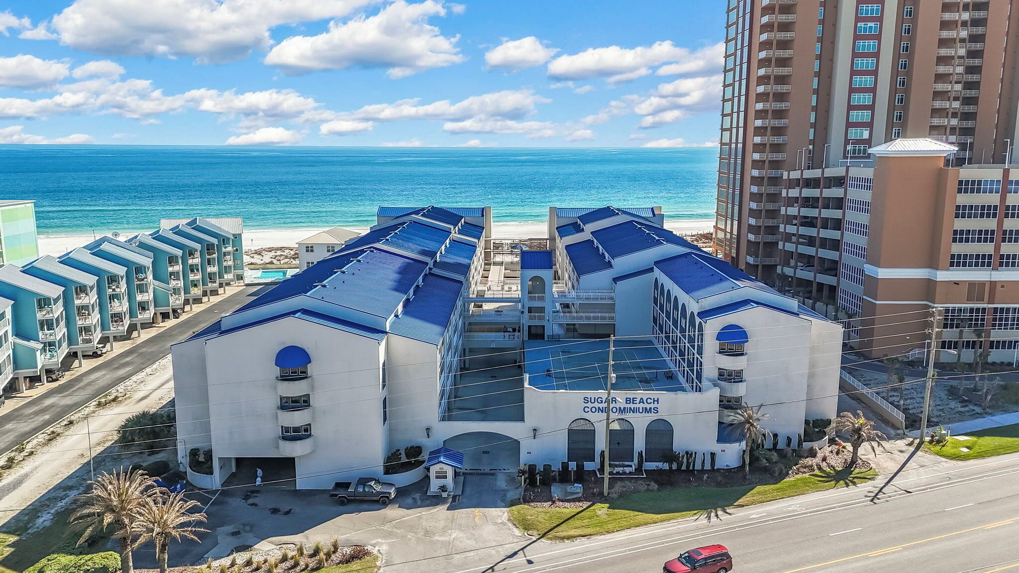 Een hotel met een witte gevel en blauw dak, gelegen nabij een strand en de oceaan.