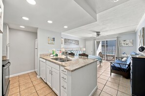 A modern kitchen with a central island, built-in appliances, and a dining area with a view.