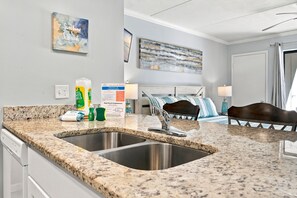 A kitchen with granite countertops, stainless steel sinks, and a breakfast bar.