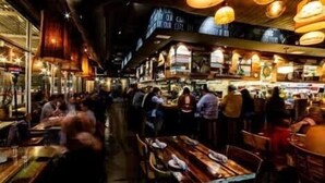 An indoor dining area with tables and chairs, overhead lighting, and a busy atmosphere. - Relaxing Wellness Escape with Sauna & Cold Plunge (Austin)