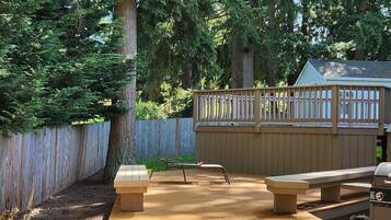 A backyard with a wooden deck, a barbecue grill, and a wooden fence.